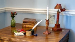 Antique desk and chair with a Christmas gift, quill, holly, candle, and books on top