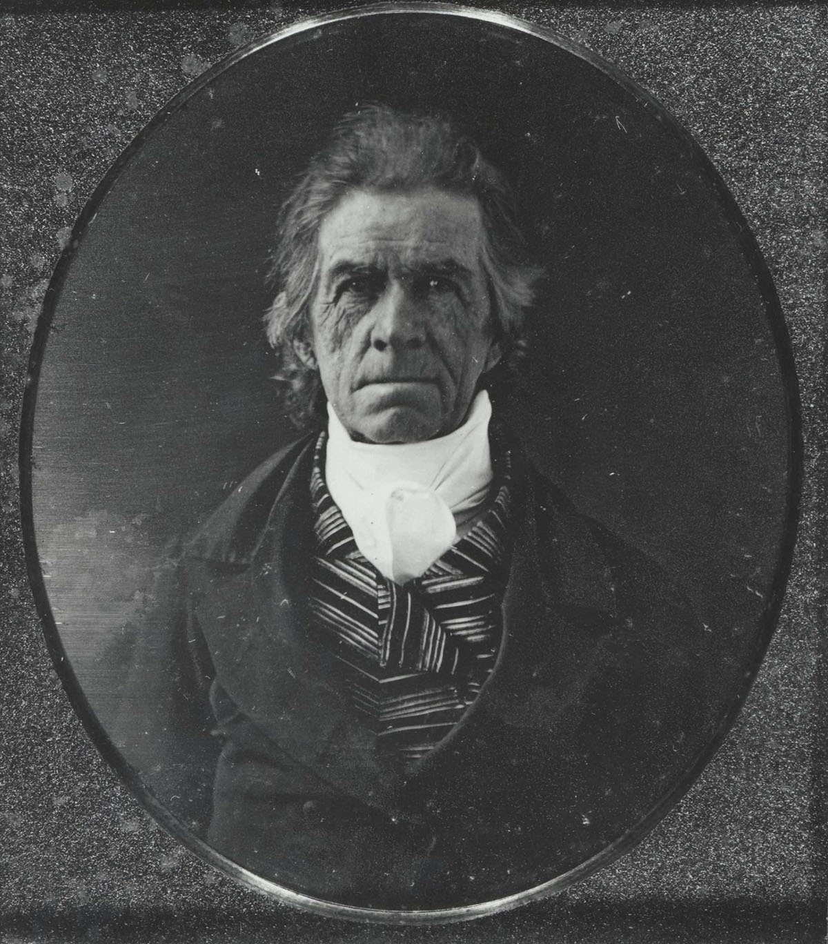 Photo of an older white man in a dark coat and striped waistcoat