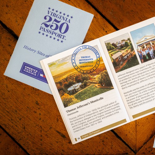 Three Virginia 250 Passport booklets lie on the parquet floor of the Monticello Parlor, with the middle one open to an information page about Monticello