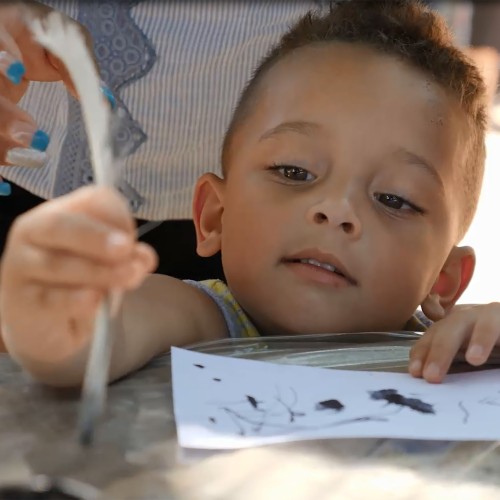 A young boy writes with a quill pen at the Mountaintop Activity Center