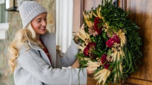 One of Monticello's expert floral designers hangs a Christmas wreath made at one of Monticello's holiday wreath workshops.