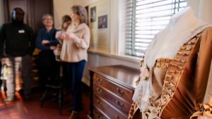 Guests on a Women at Monticello Tour listen to a guide in the South Pavilion, with a display of a replica Colonial Period dress in the foreground