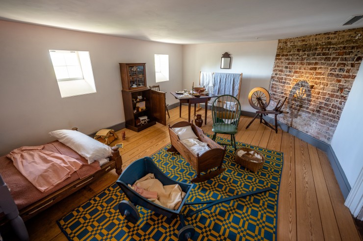 A room with small windows, a bed, a cradle and various children's toys