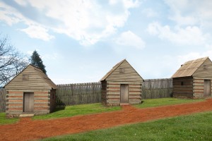 Digital recreation of three wooden slave dwellings in front of a tall wooden fence; digital image by Rendersphere, LLC