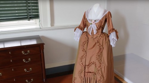Brown dress with a large lace collar draped over it.